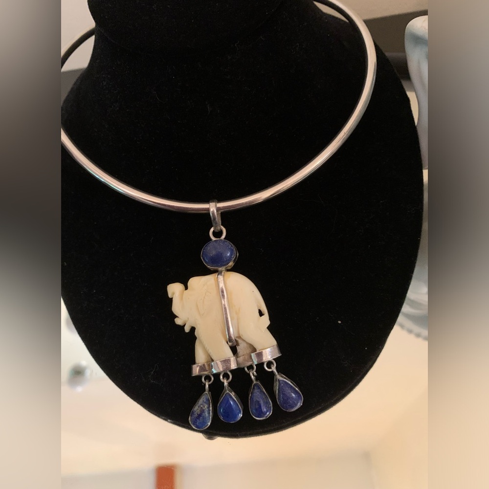 Bone colour with blue semi precious stone pendant. Real silver no stamp though.